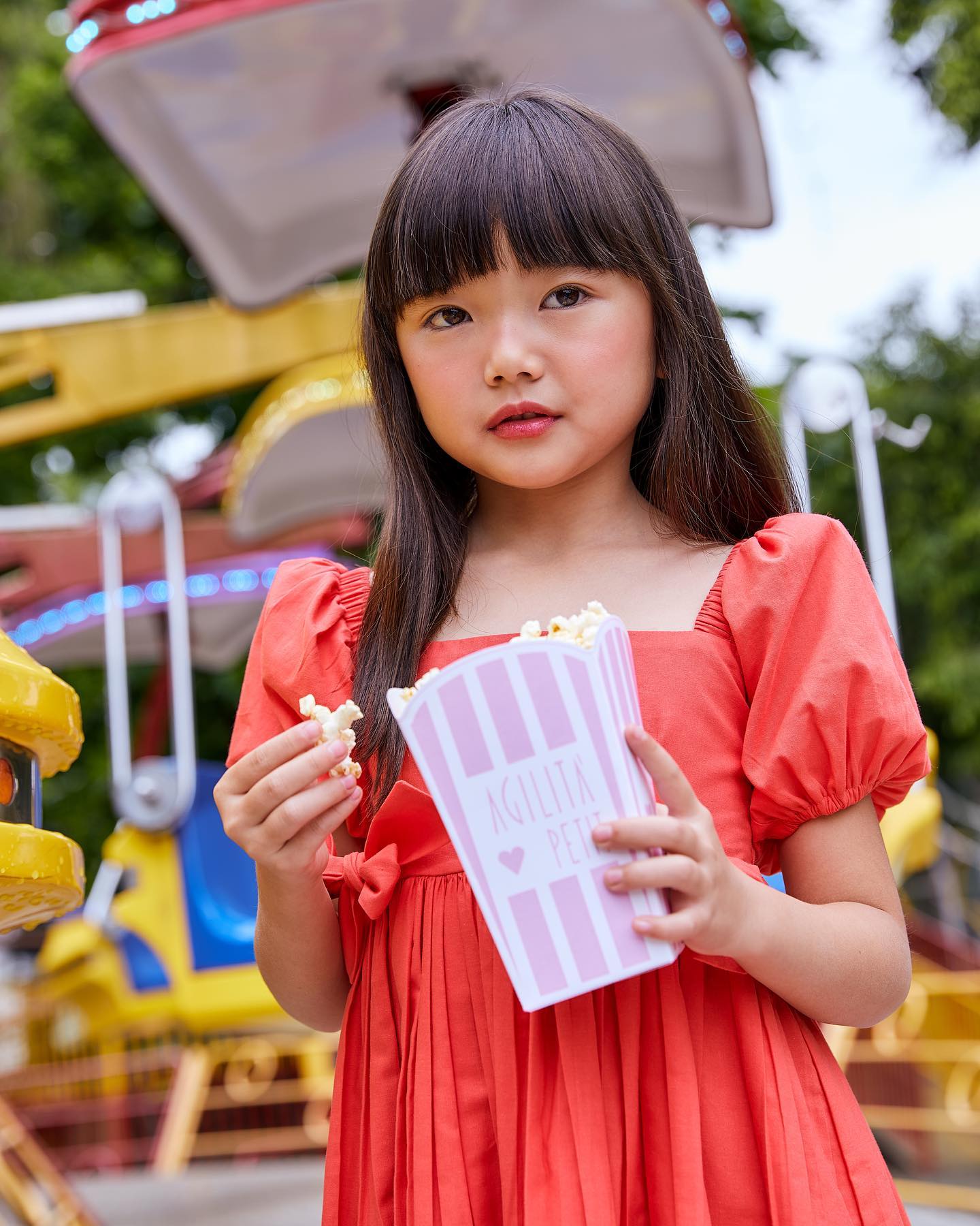 criança comendo pipoca com um vestido rosa bufante