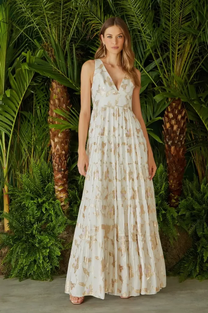 modelo utiliznaodo um vestido longo branco florido com detalhes em dourado